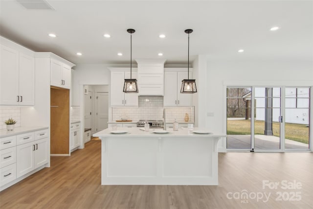 201 Plato Pl, Etowah, NC 28729 - kitchen with an island with sink, white cabinets, light countertops, and light wood-style floors