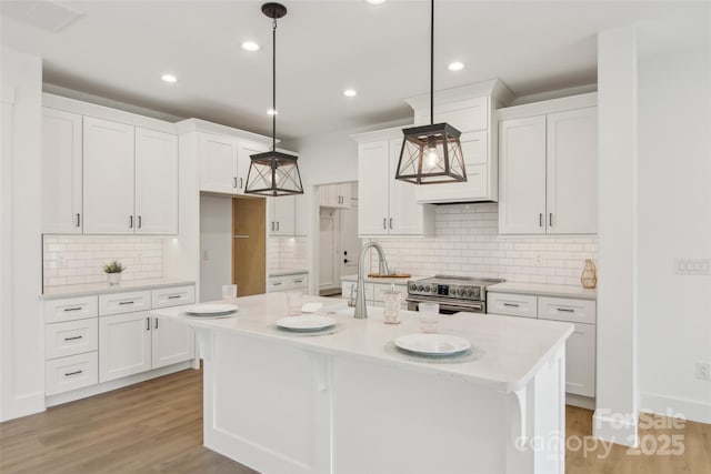201 Plato Pl, Etowah, NC 28729 - kitchen featuring light wood finished floors, light countertops, stainless steel range with electric stovetop, white cabinetry, and a kitchen island with sink