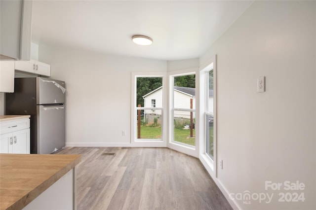 interior space featuring white cabinets, butcher block counters, stainless steel fridge, and light hardwood / wood-style floors