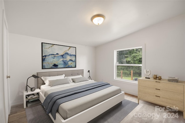 bedroom with vaulted ceiling and light hardwood / wood-style flooring