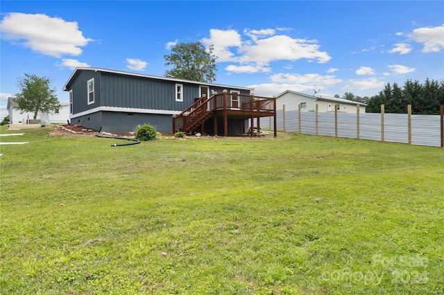 rear view of property featuring a wooden deck and a lawn