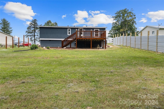 back of property with a wooden deck and a lawn