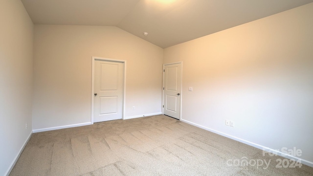 spare room with carpet and vaulted ceiling