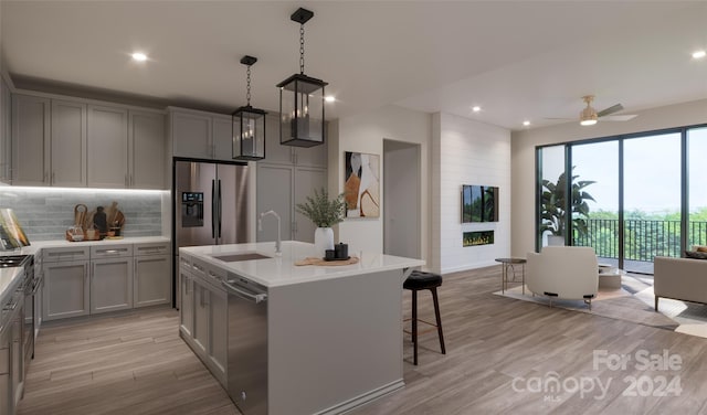 kitchen with gray cabinets, a kitchen island with sink, sink, and appliances with stainless steel finishes