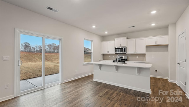 kitchen with decorative backsplash, stainless steel appliances, a kitchen island with sink, dark wood-type flooring, and white cabinetry