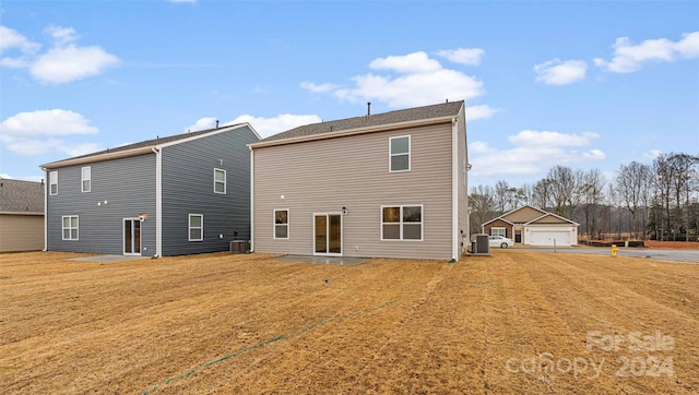 rear view of property with a yard, a garage, and central air condition unit