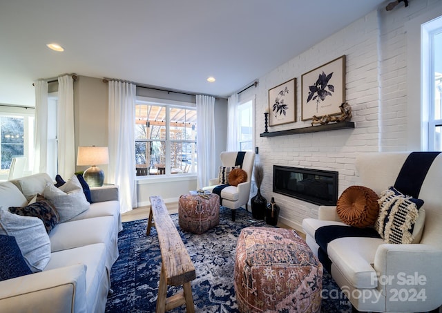 living room featuring plenty of natural light, wood-type flooring, and a brick fireplace