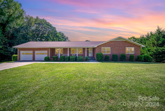 ranch-style home with a garage and a yard