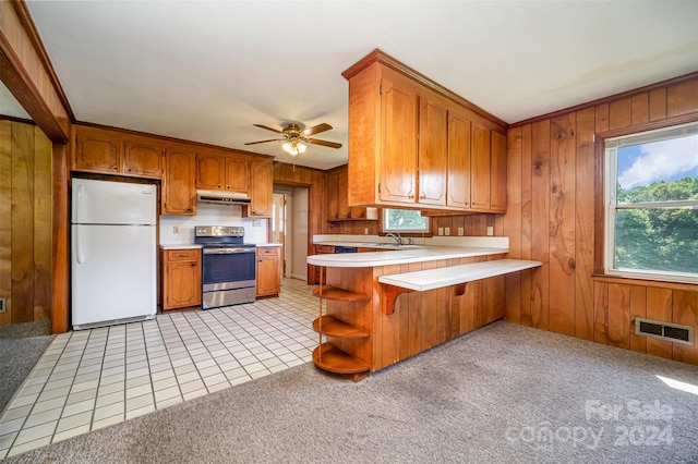 kitchen with kitchen peninsula, wooden walls, stainless steel range with electric cooktop, and white refrigerator