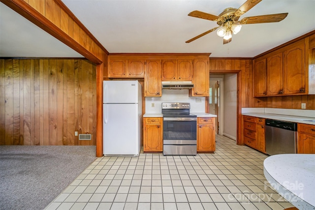 kitchen featuring appliances with stainless steel finishes, ornamental molding, wooden walls, and ceiling fan