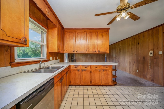 kitchen with ceiling fan, sink, light tile patterned floors, dishwasher, and wood walls