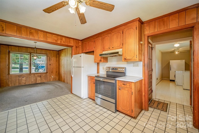 kitchen featuring washing machine and clothes dryer, wood walls, white fridge, light colored carpet, and stainless steel range with electric stovetop