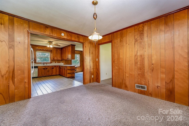 kitchen featuring pendant lighting, wooden walls, ceiling fan, light colored carpet, and kitchen peninsula