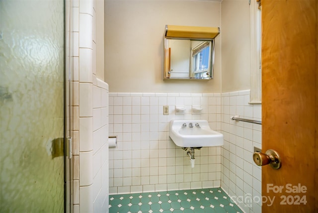 bathroom featuring an enclosed shower, sink, and tile walls