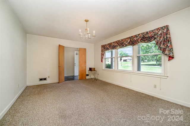 carpeted empty room with an inviting chandelier