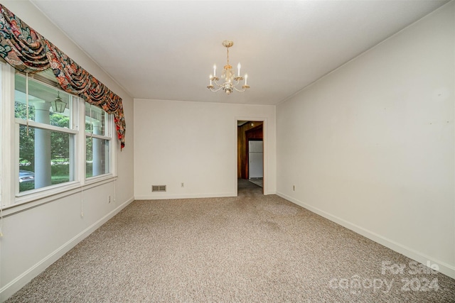 carpeted empty room with a chandelier