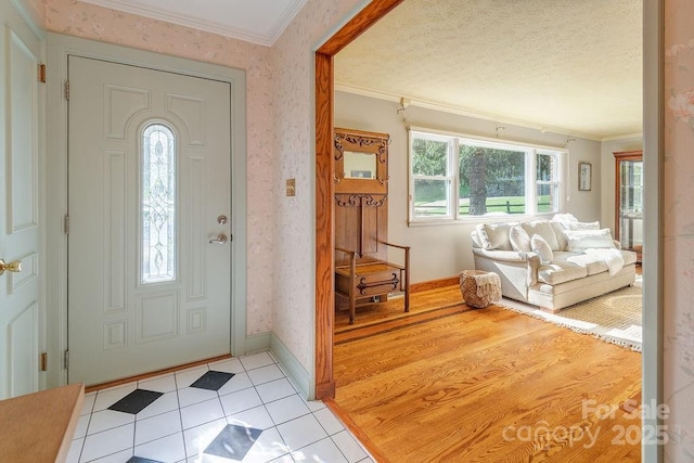 tiled entryway with crown molding and a textured ceiling