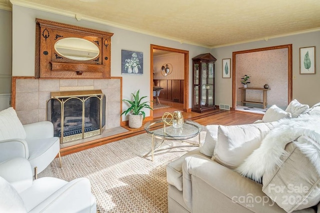 living room featuring hardwood / wood-style floors, ornamental molding, and a fireplace