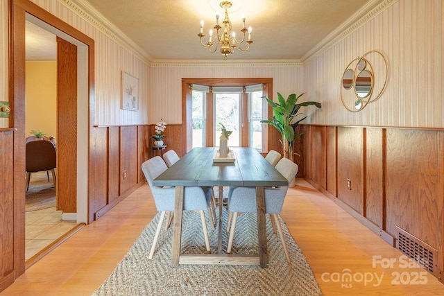 dining room featuring light hardwood / wood-style flooring, ornamental molding, and a notable chandelier