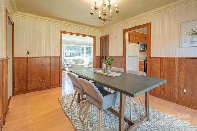 dining space with light hardwood / wood-style floors and an inviting chandelier