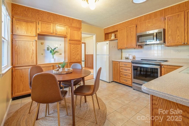 kitchen with decorative backsplash, light tile patterned flooring, and stainless steel appliances