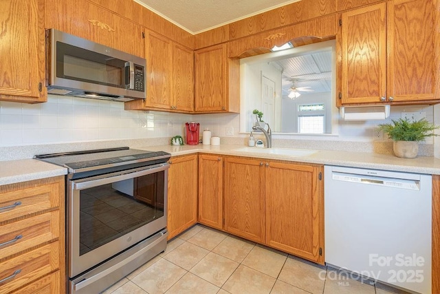 kitchen featuring backsplash, sink, ceiling fan, light tile patterned floors, and stainless steel appliances