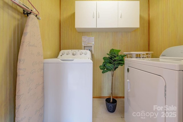 laundry area featuring cabinets, light tile patterned flooring, and washing machine and dryer