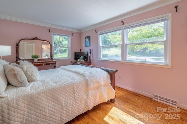 bedroom with multiple windows, crown molding, and light hardwood / wood-style flooring