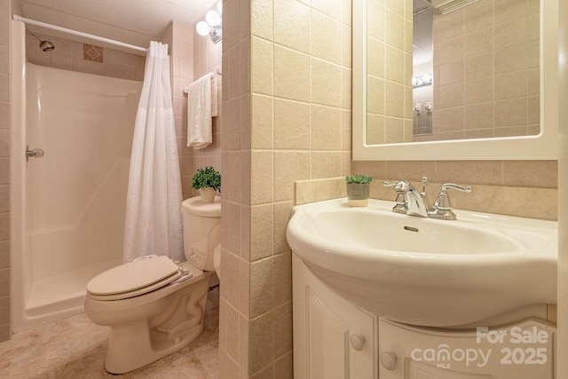 bathroom with a shower with curtain, vanity, tile walls, tile patterned flooring, and toilet