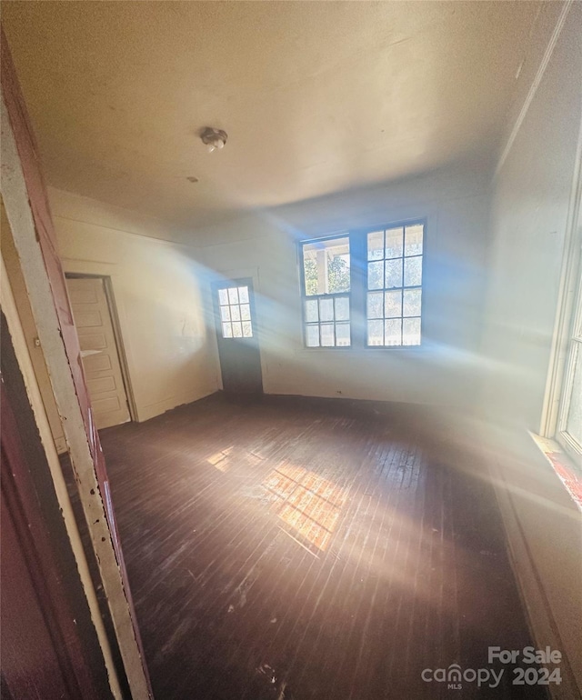 spare room featuring dark wood-type flooring and a textured ceiling