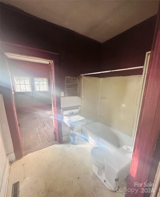 bathroom with toilet, a bathing tub, and a textured ceiling