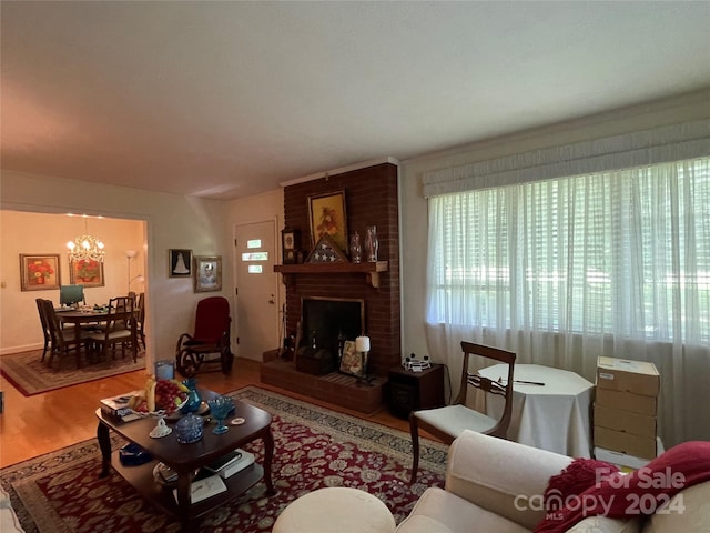 living room with a brick fireplace, wood-type flooring, and a notable chandelier