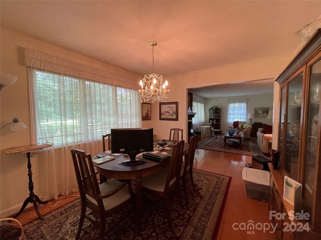 dining area featuring dark wood-type flooring, an inviting chandelier, and ornamental molding