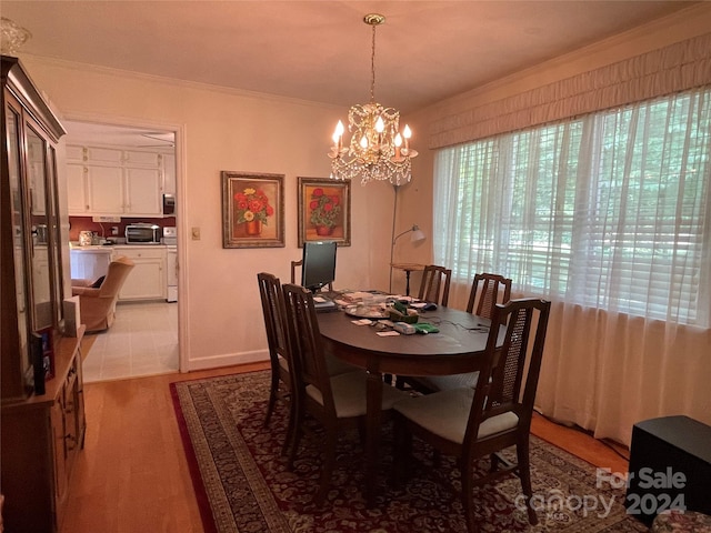 dining area featuring an inviting chandelier, crown molding, and light hardwood / wood-style floors