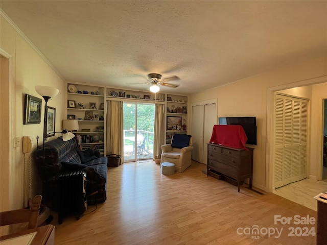 sitting room featuring ceiling fan, light wood-type flooring, built in features, and a textured ceiling