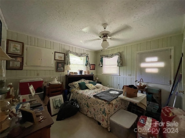 carpeted bedroom featuring ceiling fan and a textured ceiling