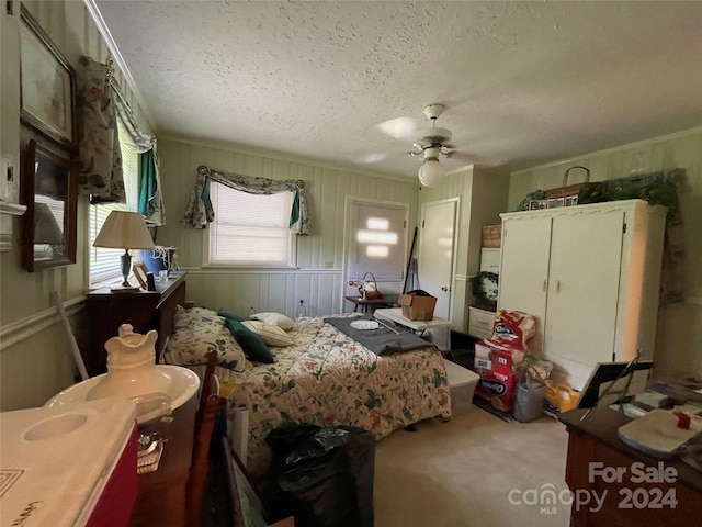 carpeted bedroom with a textured ceiling, ceiling fan, and ornamental molding