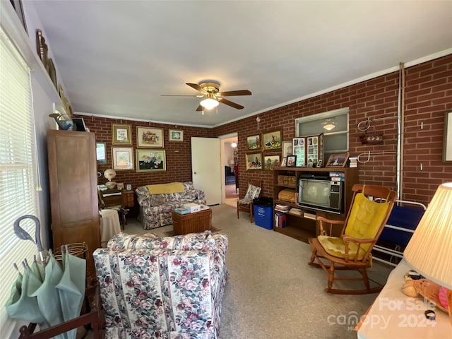 living room with ceiling fan, brick wall, carpet flooring, and ornamental molding