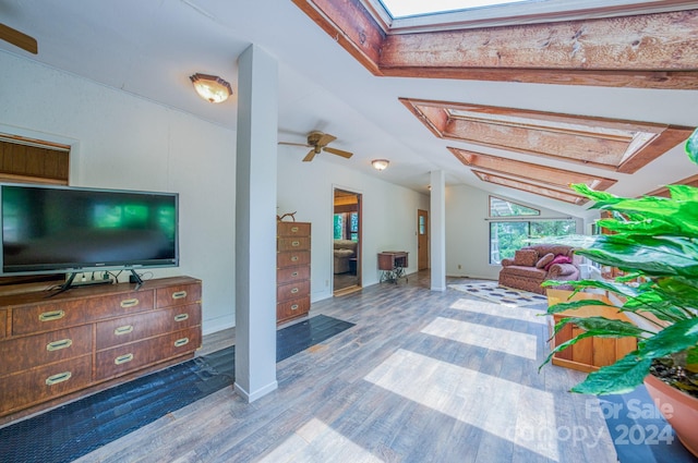 living room with ceiling fan, wood-type flooring, and lofted ceiling with skylight