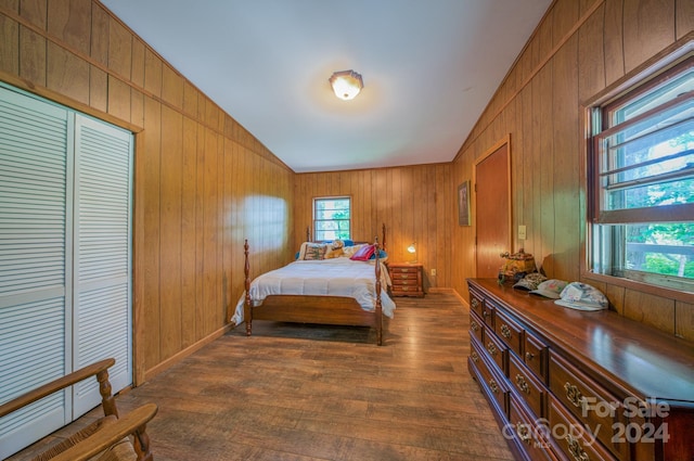 bedroom featuring vaulted ceiling, dark wood-type flooring, and wood walls