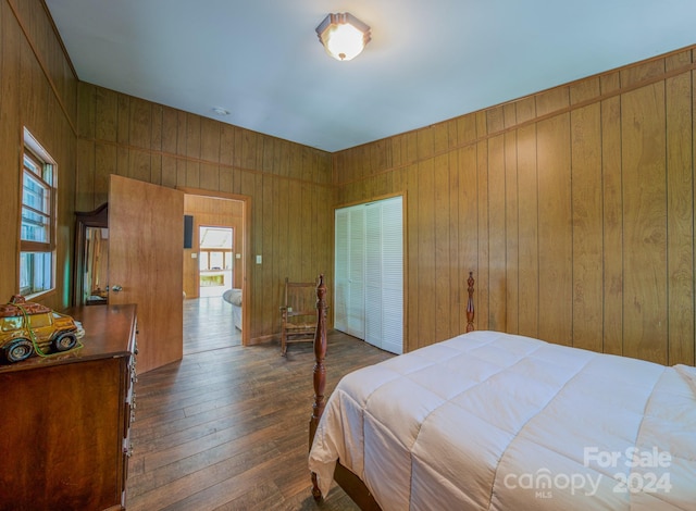 bedroom with dark wood-type flooring, a closet, and wooden walls