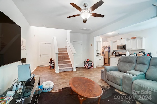 living room with ceiling fan, sink, and light wood-type flooring