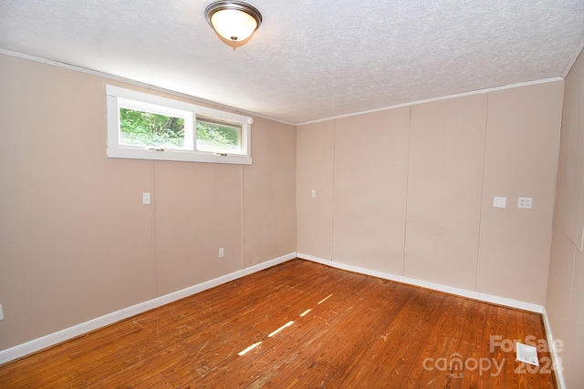 unfurnished room with a textured ceiling and wood-type flooring