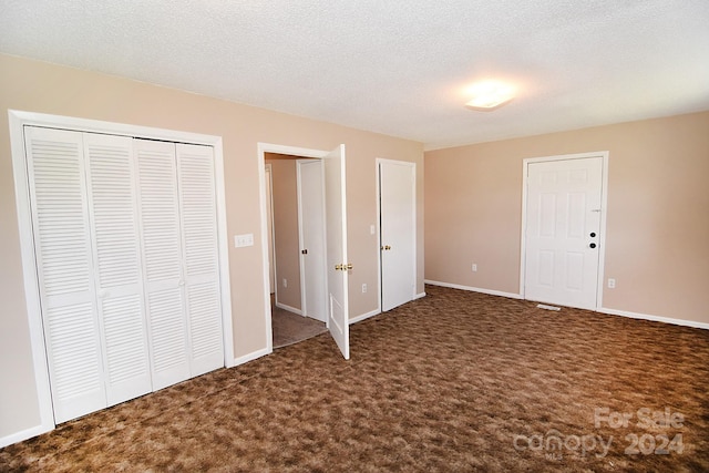 unfurnished bedroom featuring a textured ceiling, a closet, and dark carpet