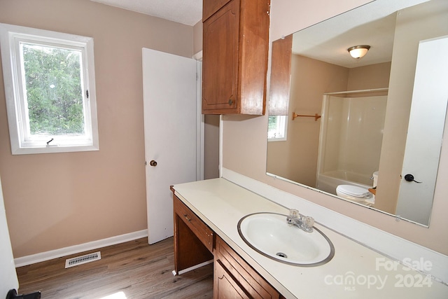 full bathroom with hardwood / wood-style floors, toilet, vanity, and a healthy amount of sunlight