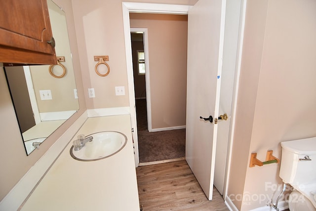 bathroom with toilet, wood-type flooring, and sink