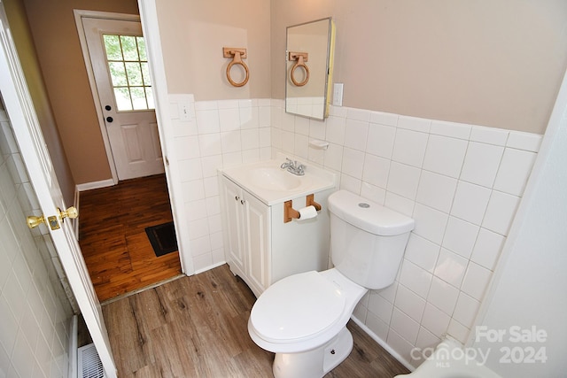 bathroom featuring hardwood / wood-style flooring, tile walls, toilet, and vanity