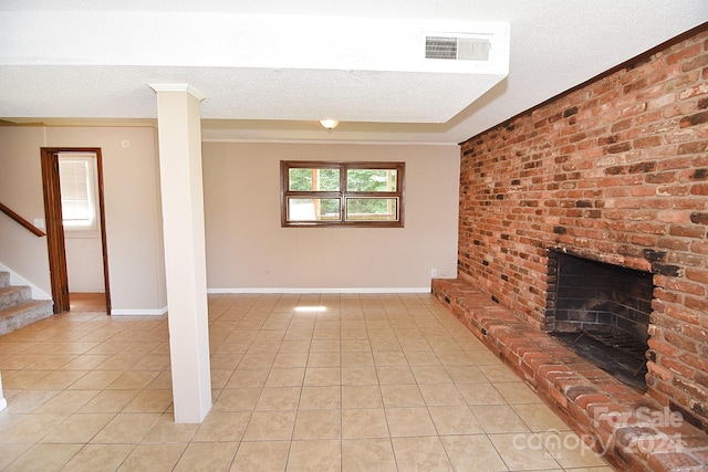 unfurnished living room featuring a brick fireplace, light tile patterned flooring, and a textured ceiling