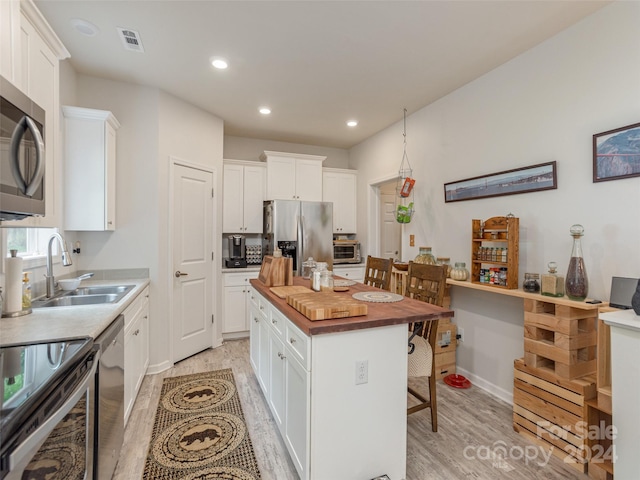 kitchen with stainless steel appliances, white cabinets, a kitchen island, and sink