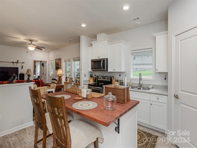 kitchen featuring sink, white cabinets, light hardwood / wood-style flooring, and stainless steel appliances